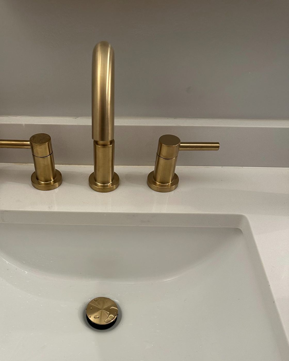 Brushed gold widespread bathroom faucet installed by SLY Residential